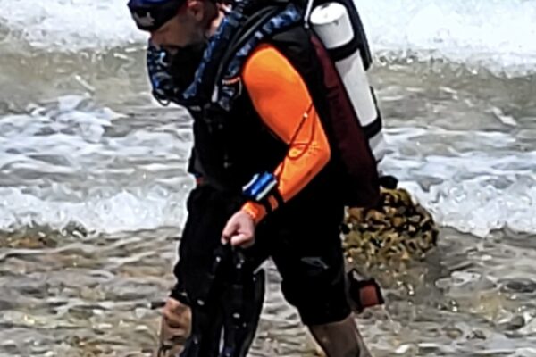Diver walking on beach wearing a Hollis PRism 2 Rebreather